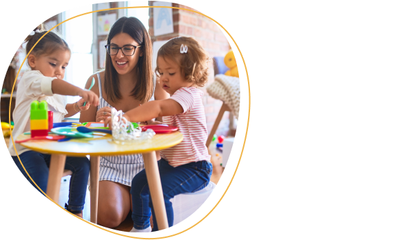 Young beautiful teacher and toddlers playing meals using plastic food and cutlery toy at kindergarten.